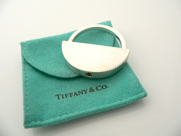 A sterling silver engravable key ring with a coin edge design, displayed on a turquoise Tiffany & Co. pouch.