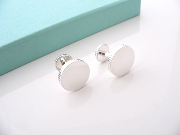 A pair of Tiffany & Co. sterling silver coin edge circle cufflinks placed on a surface.
