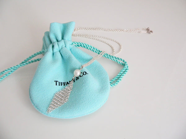 Tiffany & Co. necklace on a matching turquoise drawstring bag against a light gray background